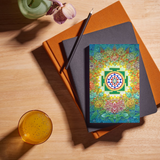 Sri Yantra Notebook featuring colorful floral and geometric design on a wooden table with books and a drink, perfect for spiritual note-taking.