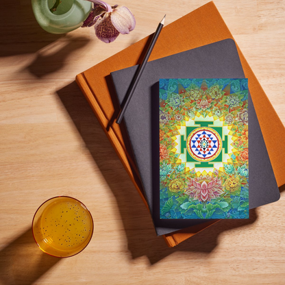 Sri Yantra Notebook featuring colorful floral and geometric design on a wooden table with books and a drink, perfect for spiritual note-taking.